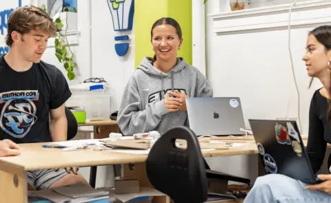 Three UNE students work around a table in the Makerspace